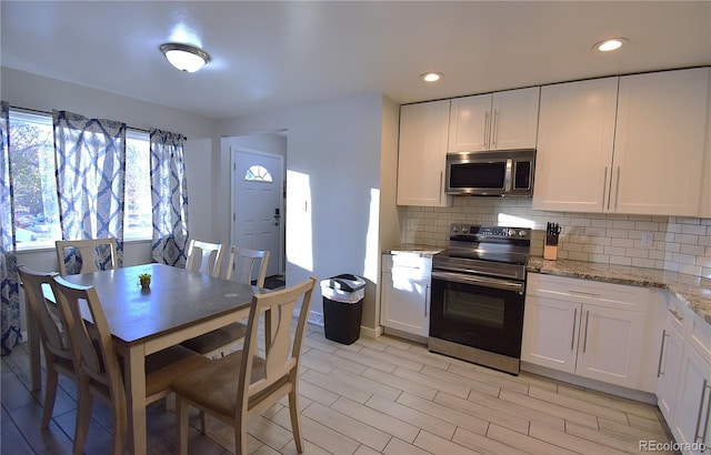 kitchen featuring white cabinets, appliances with stainless steel finishes, backsplash, and light stone counters