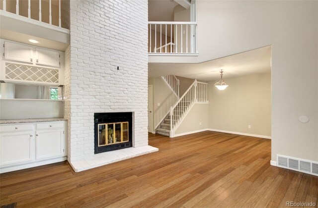 725 Crown Point Dr, Colorado Springs, CO 80906 - unfurnished living room featuring a towering ceiling, light wood finished floors, stairway, baseboards, and a fireplace