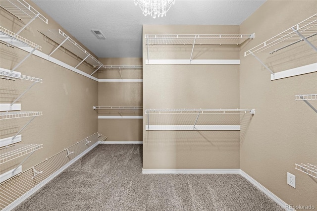 walk in closet featuring a chandelier and carpet