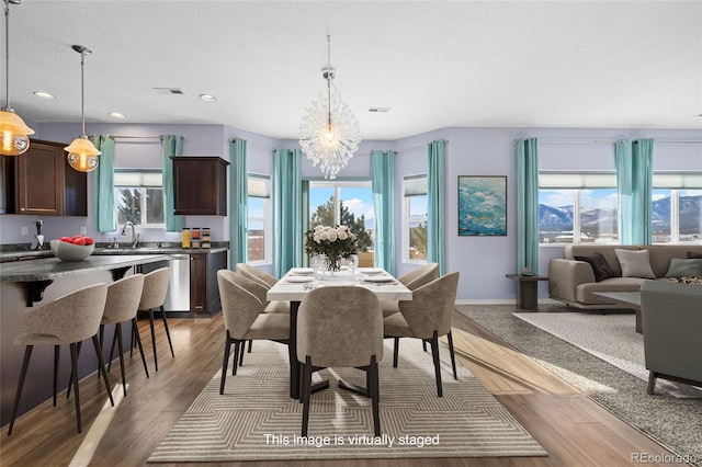 dining area with hardwood / wood-style floors, a healthy amount of sunlight, and a notable chandelier