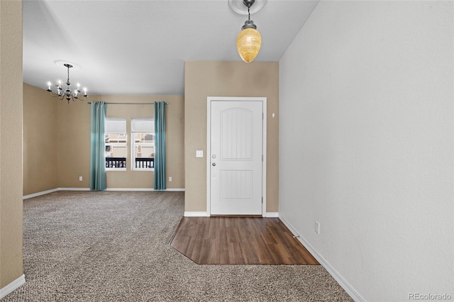 foyer entrance with dark carpet and a chandelier