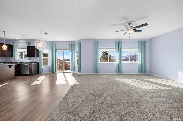 unfurnished living room featuring a textured ceiling, ceiling fan with notable chandelier, and dark hardwood / wood-style flooring