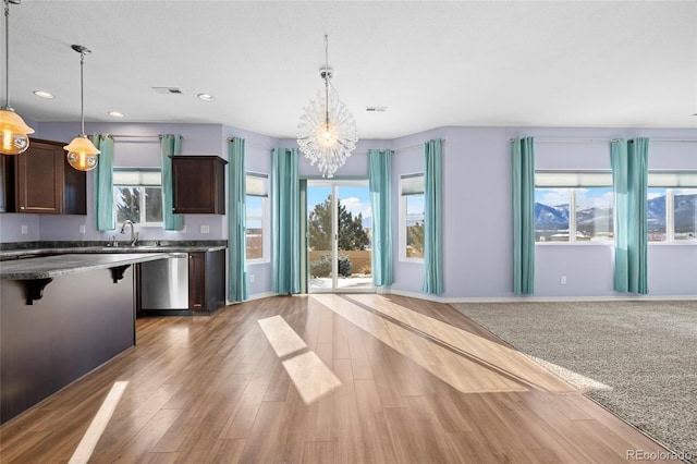 kitchen featuring light hardwood / wood-style floors, dishwasher, a chandelier, dark brown cabinets, and pendant lighting