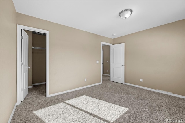 unfurnished bedroom featuring carpet flooring, a closet, and a spacious closet