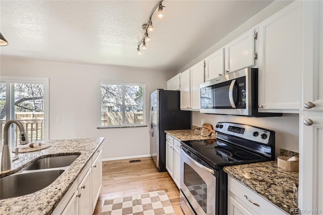 145 S Buchanan Ave, Louisville, CO 80027 - kitchen featuring appliances with stainless steel finishes, a sink, plenty of natural light, light wood-type flooring, and a textured ceiling
