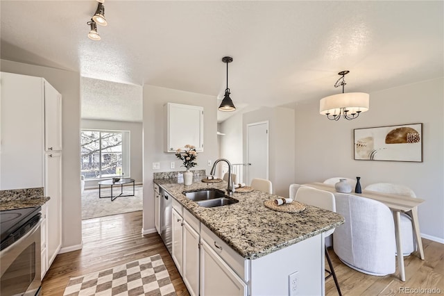 145 S Buchanan Ave, Louisville, CO 80027 - kitchen with a sink, a peninsula, white cabinets, stainless steel appliances, and light wood-style flooring