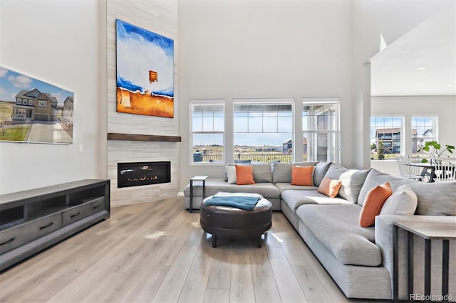 living area with a tile fireplace, wood finished floors, and a towering ceiling
