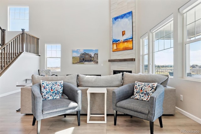 sitting room with baseboards, stairs, wood finished floors, a fireplace, and a high ceiling