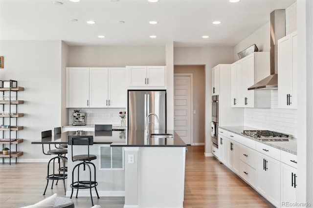 kitchen featuring an island with sink, decorative backsplash, appliances with stainless steel finishes, and a sink