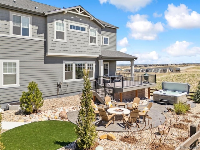 rear view of property with an outdoor fire pit, a hot tub, a wooden deck, and a patio