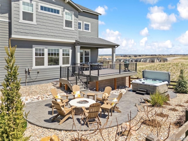 view of patio / terrace featuring a hot tub, a wooden deck, and a fire pit