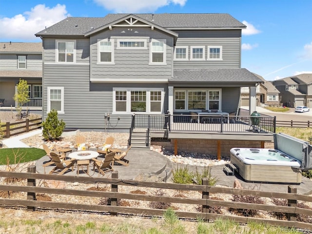 rear view of property featuring a patio, an outdoor fire pit, a deck, a hot tub, and a fenced backyard