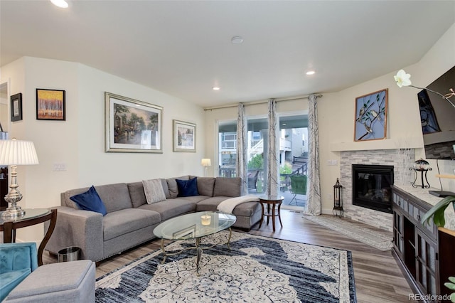 living room with hardwood / wood-style floors and a stone fireplace