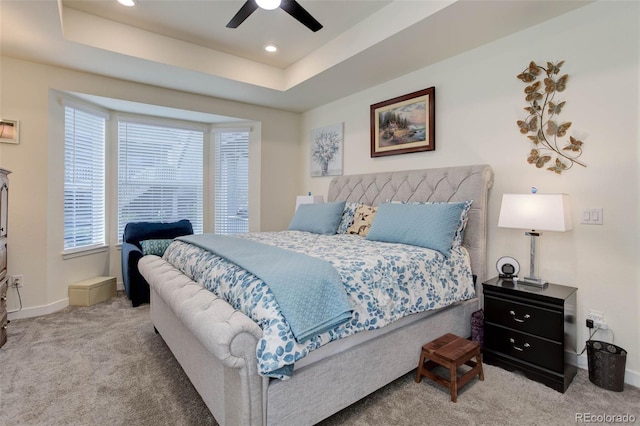 carpeted bedroom with a tray ceiling and ceiling fan