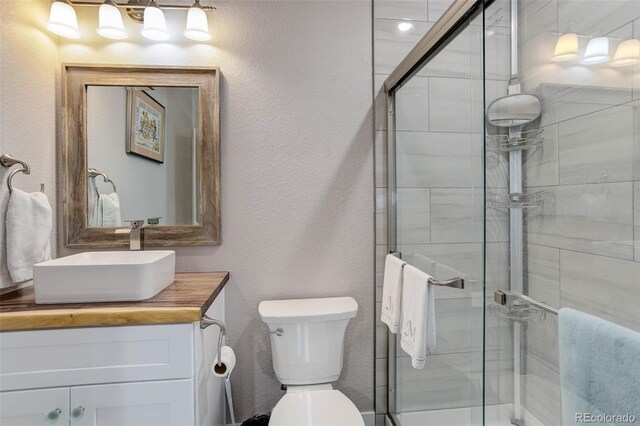 bathroom with toilet, vanity, and an enclosed shower