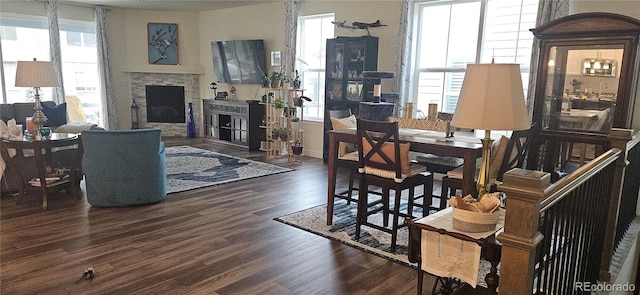 dining room with a fireplace, dark wood-type flooring, and a healthy amount of sunlight