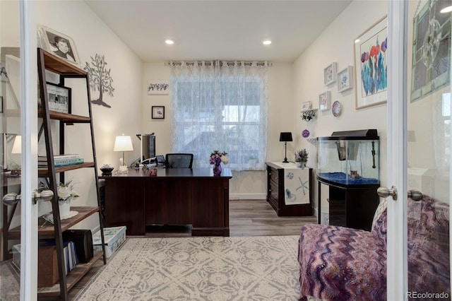 office with light wood-type flooring and french doors