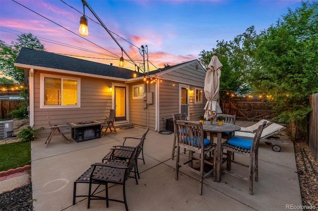 5125 Umatilla St, Denver, CO 80221 - patio terrace at dusk with a fire pit, a fenced backyard, a patio area, outdoor dining space, and cooling unit
