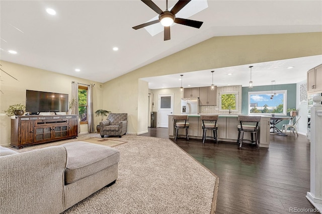 living room featuring ceiling fan, plenty of natural light, vaulted ceiling, and dark hardwood / wood-style floors