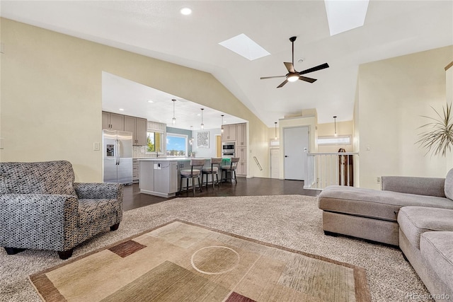 living room with ceiling fan, sink, lofted ceiling with skylight, and dark hardwood / wood-style flooring