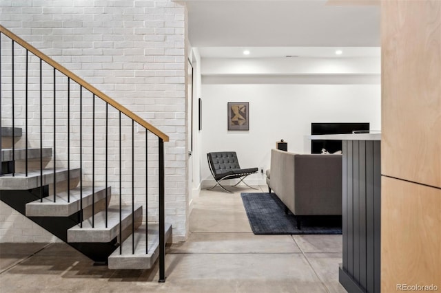 staircase featuring brick wall and concrete flooring