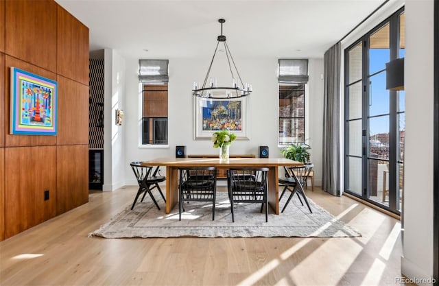 dining area with floor to ceiling windows, a chandelier, and light hardwood / wood-style floors