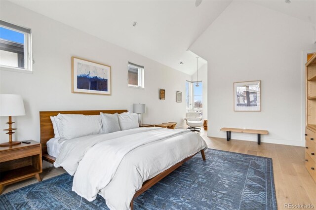 bedroom with multiple windows, lofted ceiling, hardwood / wood-style floors, and connected bathroom