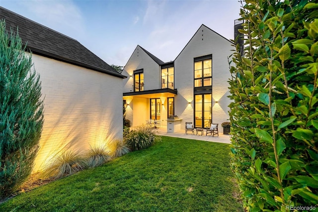 rear view of property with a yard and a patio area