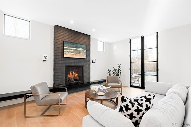 living area with a fireplace, a wall of windows, wood finished floors, and recessed lighting