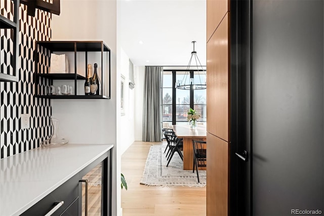 interior space with wine cooler, expansive windows, light wood finished floors, and an inviting chandelier