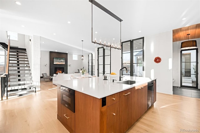 kitchen featuring a fireplace, open floor plan, a large island, stainless steel dishwasher, and modern cabinets