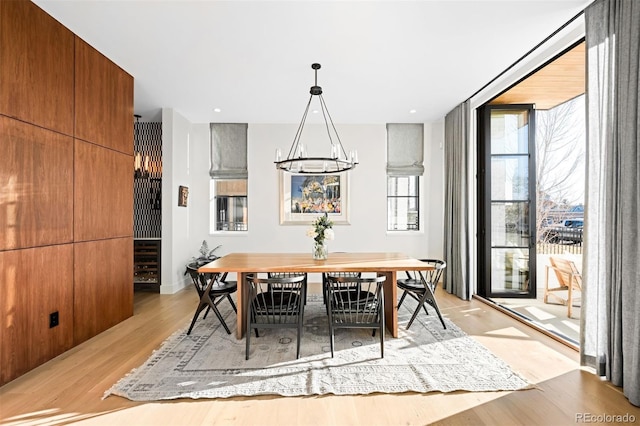 dining room with a wall of windows, light wood-type flooring, and a notable chandelier