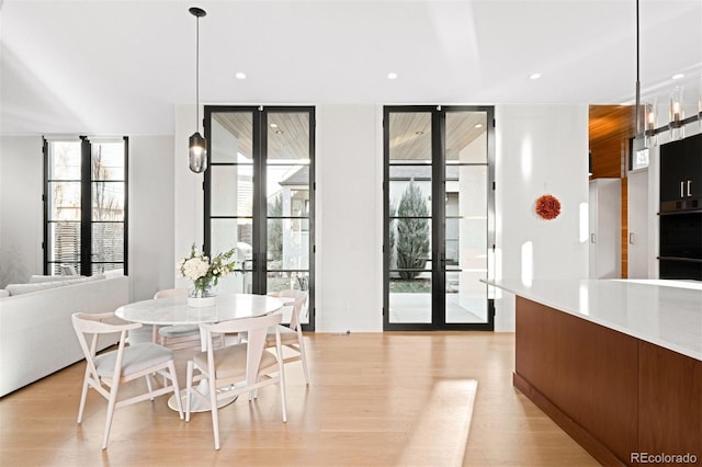 dining room featuring expansive windows, french doors, light wood-type flooring, and recessed lighting