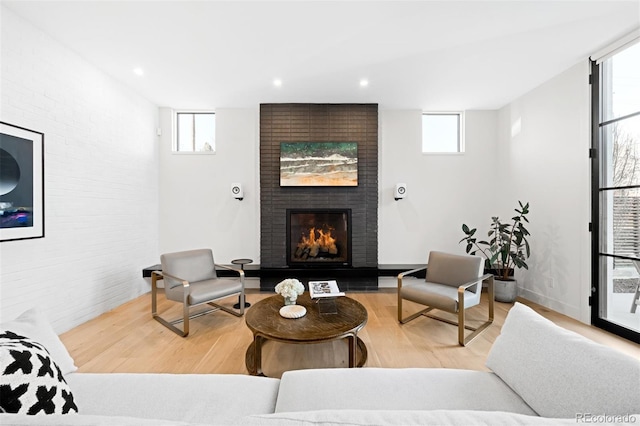 living area with a brick fireplace, wood finished floors, and recessed lighting