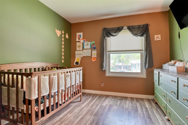 12 Arrawanna St, Colorado Springs, CO 80909 - bedroom with wood finished floors, a crib, and baseboards