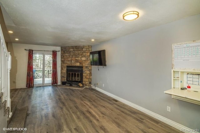 unfurnished living room with a stone fireplace, dark wood-type flooring, and a textured ceiling