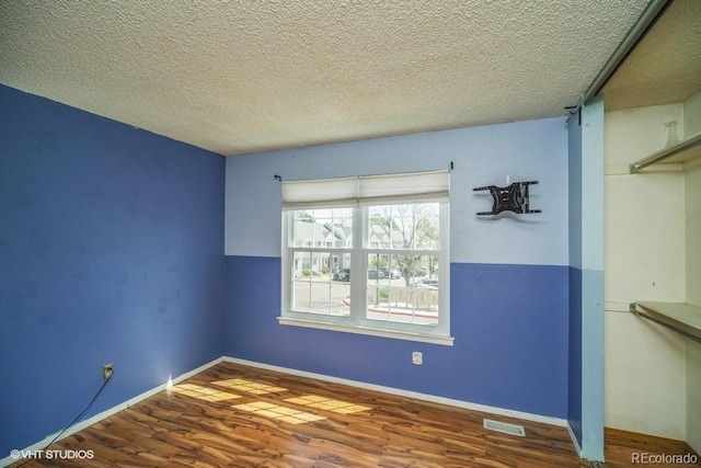 unfurnished room with wood-type flooring and a textured ceiling