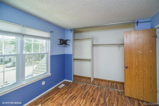 unfurnished bedroom with dark hardwood / wood-style floors, a textured ceiling, and a closet