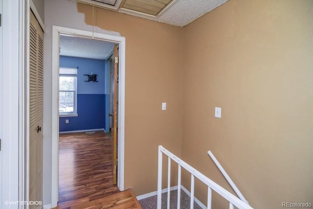 hall featuring wood-type flooring and a textured ceiling