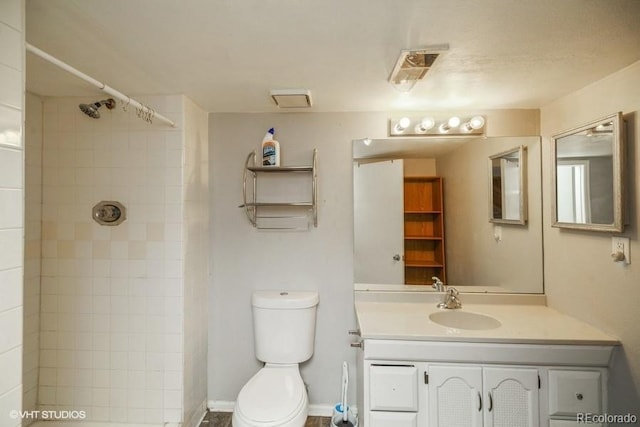 bathroom with vanity, toilet, and tiled shower