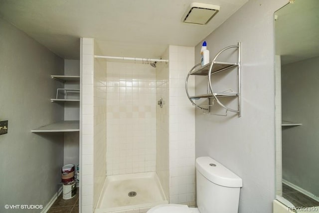 bathroom with tile patterned flooring, tiled shower, and toilet