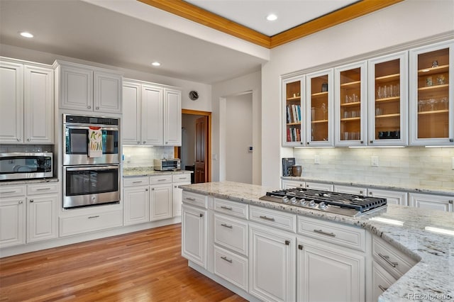1999 Champions Cir, Castle Rock, CO 80104 - kitchen with appliances with stainless steel finishes, backsplash, white cabinetry, light wood-style flooring, and recessed lighting