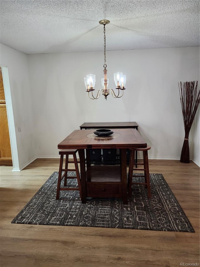 dining area with a chandelier, wood finished floors, and a textured ceiling