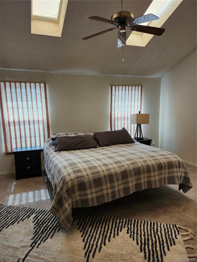 bedroom featuring a skylight, carpet flooring, a textured ceiling, and ceiling fan