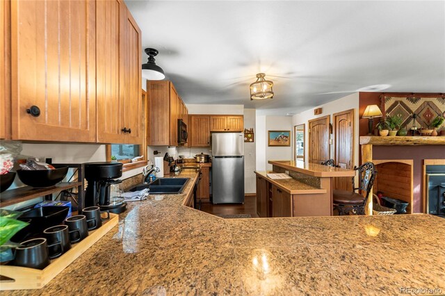 609 Brook Dr, Idaho Springs, CO 80452 - kitchen featuring freestanding refrigerator, a sink, black microwave, brown cabinetry, and a center island