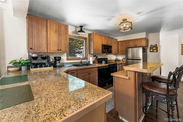 609 Brook Dr, Idaho Springs, CO 80452 - kitchen with black appliances, a sink, a kitchen breakfast bar, a center island, and brown cabinets