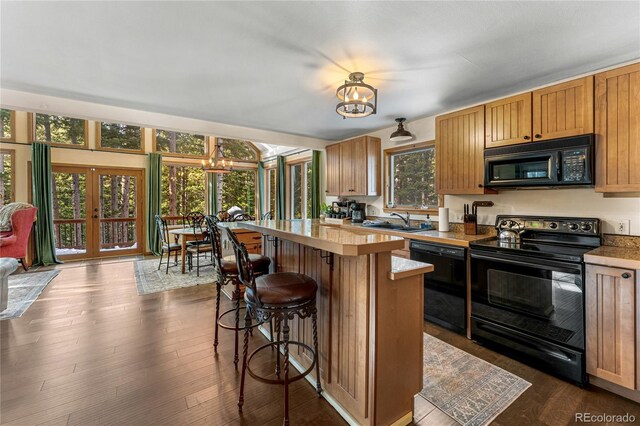 609 Brook Dr, Idaho Springs, CO 80452 - kitchen featuring black appliances, a chandelier, a sink, light countertops, and a kitchen breakfast bar