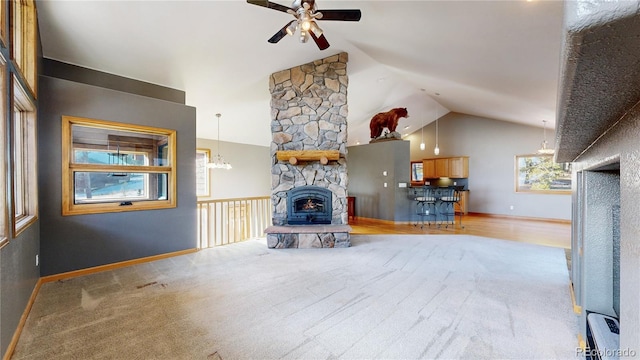 unfurnished living room with baseboards, a fireplace, high vaulted ceiling, and ceiling fan with notable chandelier