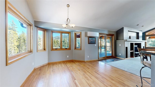 interior space with a large fireplace, baseboards, a chandelier, and wood finished floors