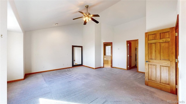 unfurnished bedroom with baseboards, ceiling fan, ensuite bathroom, carpet floors, and high vaulted ceiling